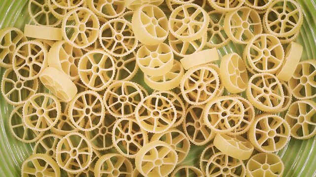 Rotating video close-up of Ruote pasta with wheel-shaped patterns and textured edges, showcasing golden wheat color and playful Italian cuisine design in smooth continuous motion.