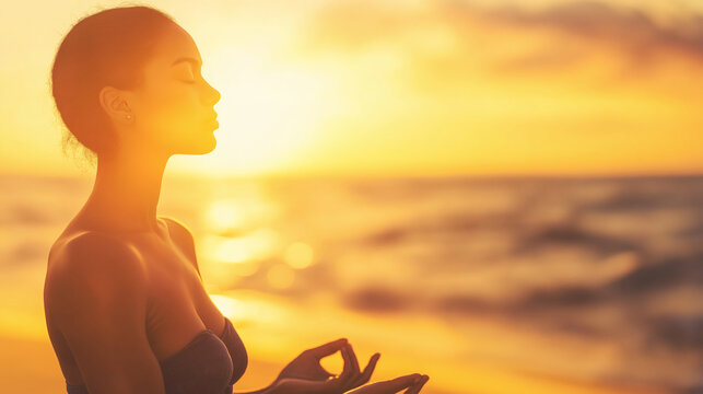 Side view of serene young woman meditating on beach at sunset, practicing yoga and finding inner peace by the ocean