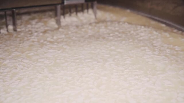 4k close up footage of mechanic arms mixing hot milk at the dairy factory. closeup of wire frames rotating in automated heating vat at cheese plant, cutting yellow mass into pieces and separating it f