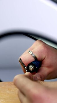 Crafting Metal Key. Engaged In Careful Manual Shaping Of Metal Key Blank Using Small Tools On Workbench