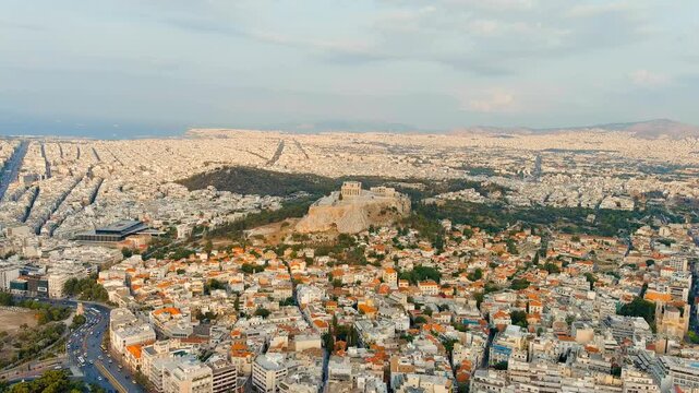 Athens, Greece. The Acropolis of Athens, ancient citadel crowned by the Parthenon and classical marble temples, aerial panoramic view in warm morning summer light over the urban grid. Drone footage, 