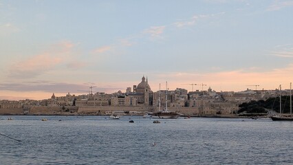 Naklejka premium View of Valletta behind various boats sailing in the evening in Malta island