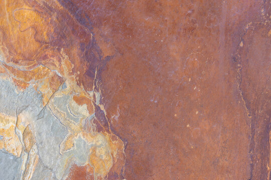 Texture of natural rusty slate stone. Rough brown and gray shale rock surface background