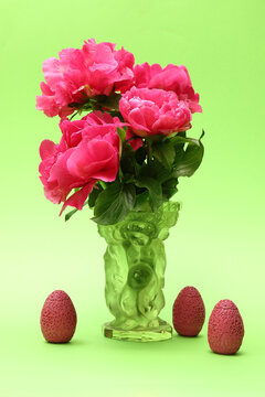 Peonies in a glass vase and three colorful objects with a pressed patterns. All on a light background. Photo with maximum depth of field.