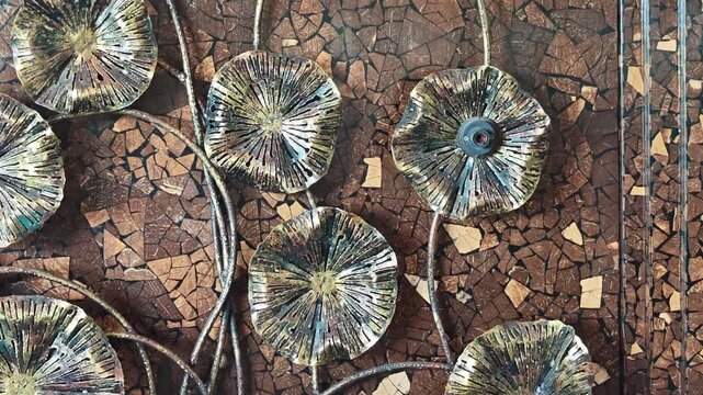 A beautifully patterned wall; a wall made of coconut shell decorated with silver metal flowers.