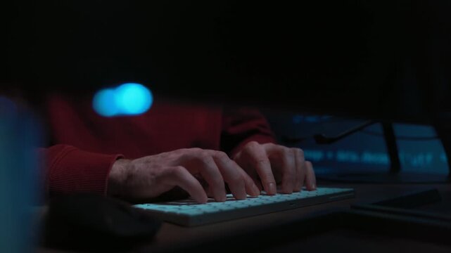Close-up of a software engineer hands actively typing code on a keyboard in a dark office, works late at night on a complex programming or hacking-related script. Space for text