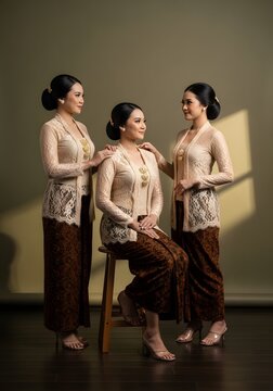 Three women in traditional Indonesian Kebaya posing in a studio setting with warm lighting