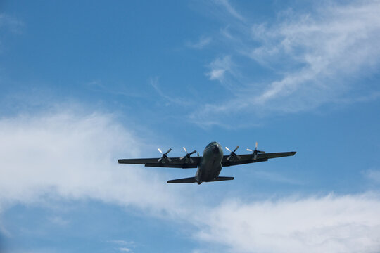 Four-Engine Turboprop Military Transport Aircraft Taking Off into Blue Sky with Clouds