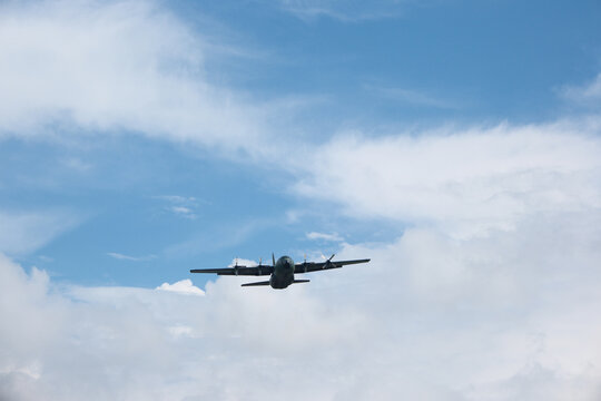 Four-Engine Turboprop Military Transport Aircraft Taking Off into Blue Sky with Clouds