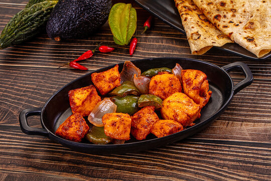 Indian Paneer Tikka Masala inl with Roti bread on a dark wooden table