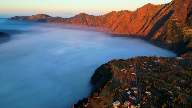 Cinematic aerial view of Mount Bromo volcano at sunrise &ndash; Breathtaking drone shot of smoking crater and mystical sea of sand covered in morning mist, East Java Indonesia landscape 4k