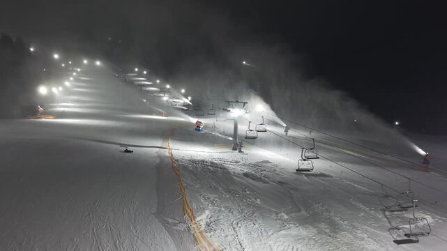 Lit Slopes With Snow Cannons. Serene Nighttime Ski Slopes With Bright Lights And Snowmaking Equipment