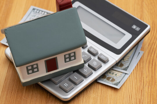 House on a calculator with money on a desk for mortgage payments