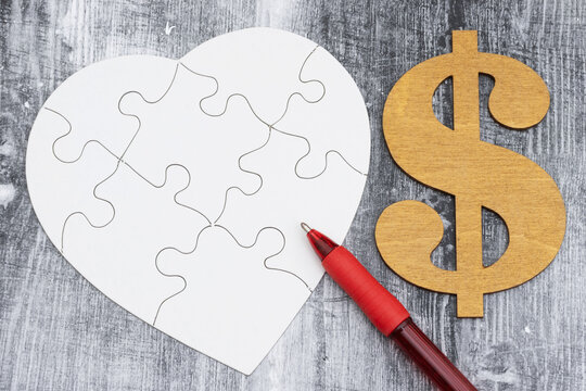 Blank white puzzle heart with dollar sign and pen on a weathered wood desk for prenup