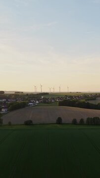 Vertical Aerial View of Village and Wind Turbines at Sunset