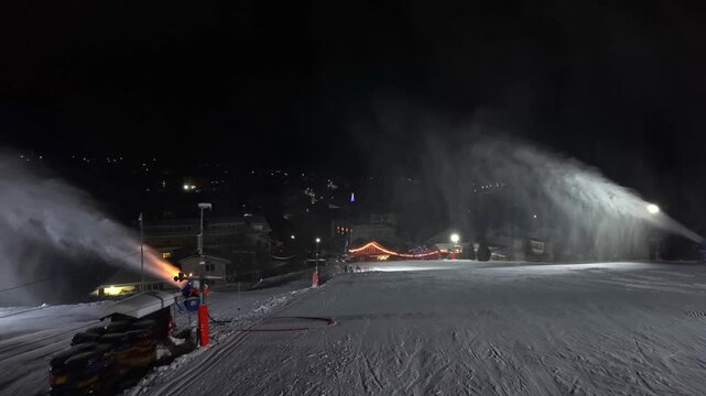 Worker In Bright Orange Jacket Performing Detailed Service On Snow Production Device During Nighttime