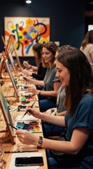 Fototapeta premium Women paint on canvas and drink wine at a social art class. Friends enjoy creative fun together, learning new skills and relaxing. This gathering offers leisure and artistic expression in a studio.