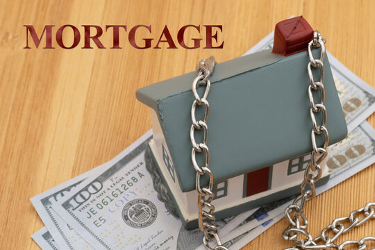 Mortgage text with a house with a silver chain with money on a desk for mortgage payments