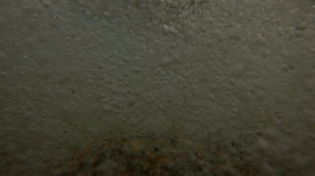 Sea waves crush the pebble rocks of the beach and throw them into the camera lens, Underwater split level, Slow motion. Splashes of sea storm water foam