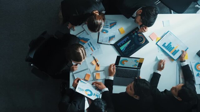 Top down aerial view of smart business man join meeting and present financial plan while diverse business people discuss and brainstorm marketing idea at table with marketing document. Directorate.