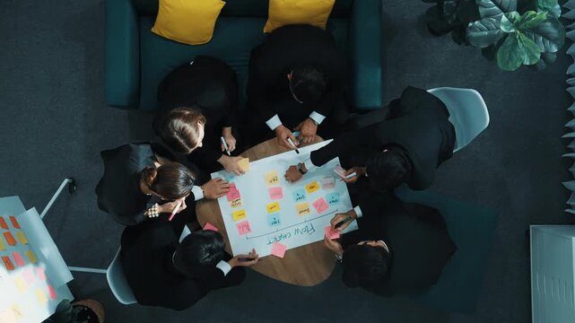 Top down view of smart business people hands making scrum task board to manage workflow in workplace. Diverse marketing team drawing a line and use colorful stick notes to work on kanban. Directorate.