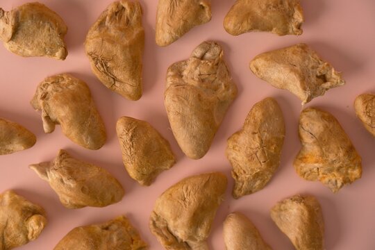 Top view of premium freeze-dried meat pet food treats scattered on a pastel pink background. Healthy, natural dehydrated chicken hearts for cats and dogs. Minimalist studio shot for animal nutrition.