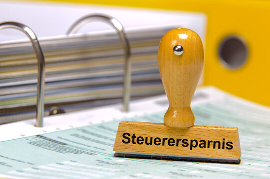 Ein Holzstempel ist bedruckt mit der Aufschrift: Steuerersparnis