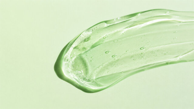 transparent green gel smear on light green background. Cosmetic skincare product texture. Moisturizing serum, aloe vera extract or antiseptic sanitizer. Beauty and health care concept