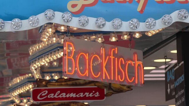German fried fish neon sign flashing at a food stall