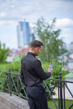 Relaxed businessman from back using smartphone on city background with copy space