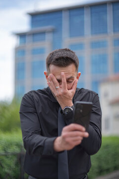 Disappointed businessman doing facepalm gesture with smartphone and copy space