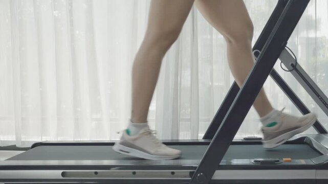 A person exercising on a treadmill indoors, focusing on maintaining fitness and health in a modern environment.