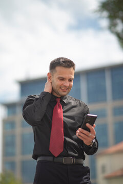 Relieved businessman smiling at smartphone with red tie and copy space