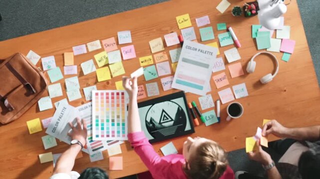 Top view of smart designer holding color palette while project manager looking at design and choosing color for program. Professional businesswoman taking a note while design creative logo. Symposium.
