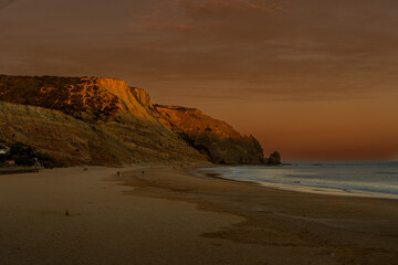 Golden hour sunset over the Atlantic Ocean shoreline with rolling hills, warm light reflecting on the water and a scenic coastal landscape. © Vaidile