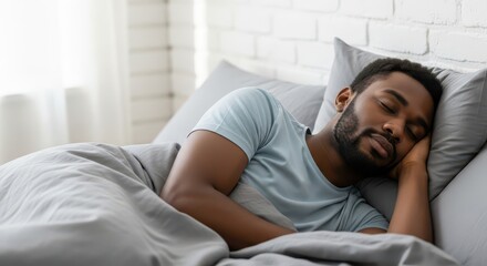 Fototapeta premium Peaceful Young African American Man Sleeping Soundly in Comfortable Bed at Home in Bright Bedroom