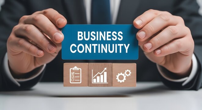 Businessman holding blue card with text 'business continuity' and wooden blocks with icons