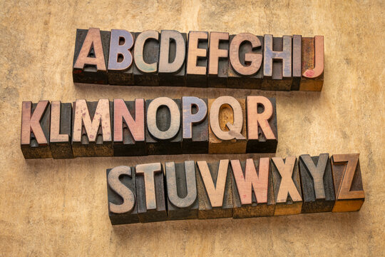 English alphabet in vintage letterpress wood type printing blocks against art paper
