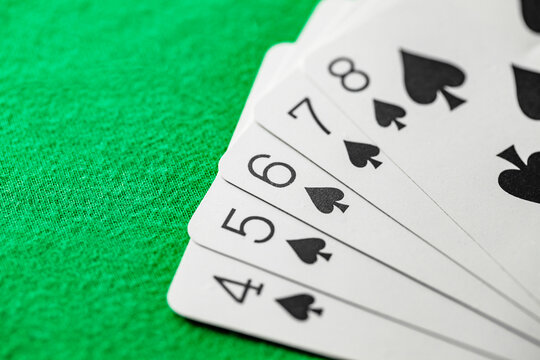 straight flush of spades from playing cards in poker on green cloth