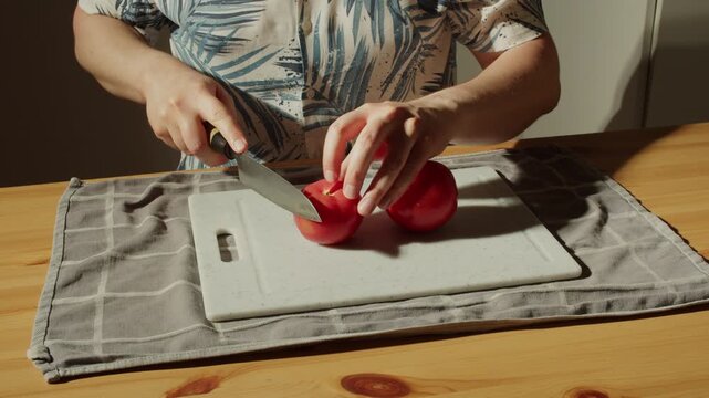 Man in Hawaiian Shirt Slicing Red Tomato with Japanese Knife in Warm Morning Kitchen Light