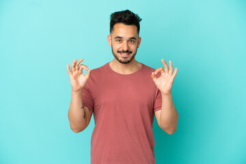 Fototapeta premium Young caucasian man isolated on blue background showing ok sign with two hands