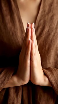 Vertical video: Clip opening showing hands holding prayer pose with French nails and brown fabric