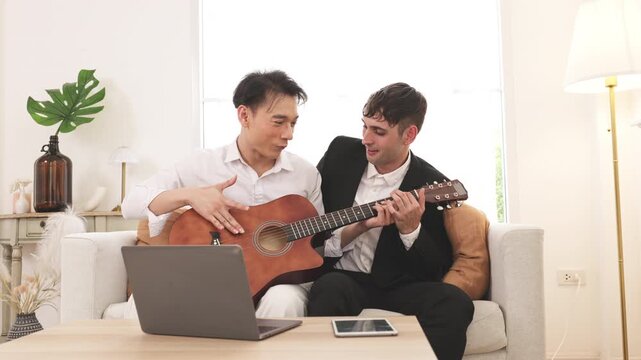 Friends learning guitar with laptop at home