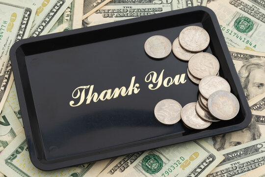 Thank You text on a tip serving tray on twenty dollar bills and coins for tipping culture