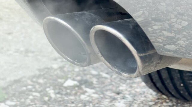 The twin chrome tailpipes release a steady stream of white exhaust fumes. This continuous release creates a faint, low-frequency hum combined with a soft, misty whoosh sound.