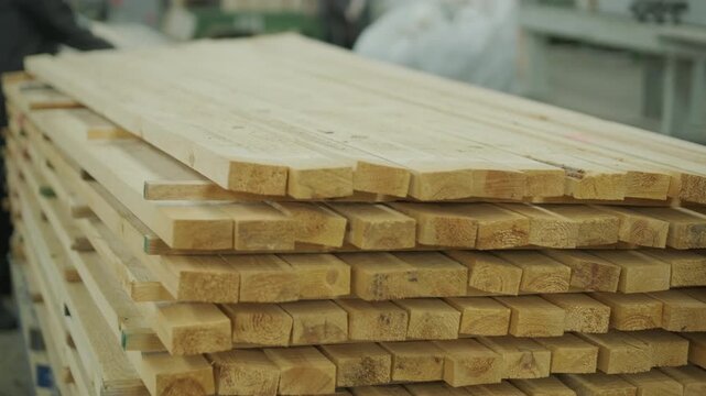 A large industrial warehouse featuring a forklift operating among stacks of dried wooden planks prepared for further furniture or flooring production