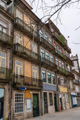Fototapeta premium Row of historic residential buildings in Porto featuring ornate iron balconies, colorful facades, and traditional ceramic tile details in an old European street.