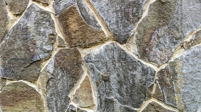 An outdoor wall made of irregular flagstones and mortar with rustic gray and brown shades