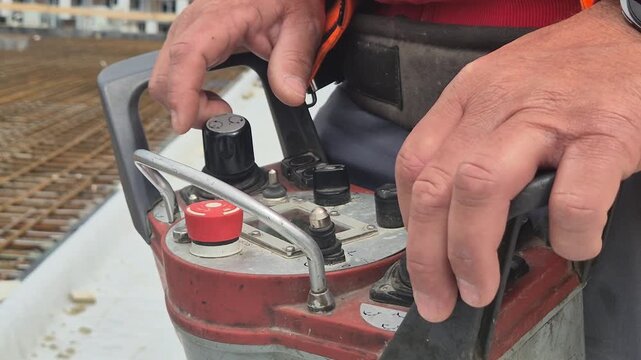 Close up video of an operator holding and controlling a concrete pump with a wireless remote control console in slow motion.