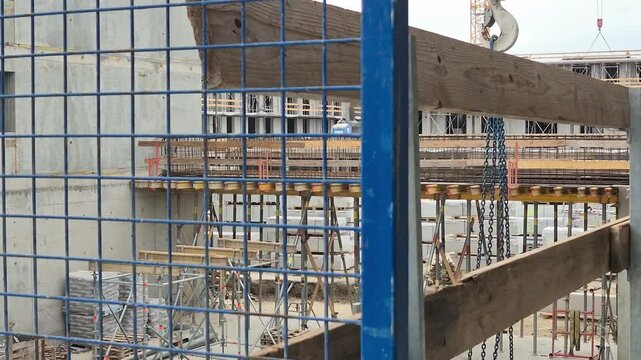 Tower crane hook block with chains moving past an outrigger platform shot from a high floor level in normal speed.